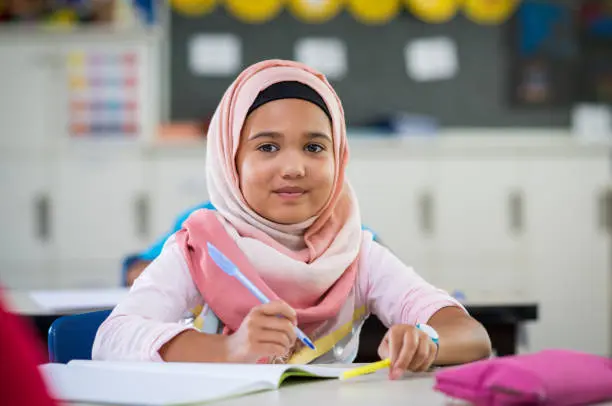 A kid reading Quran online, wearing headphones